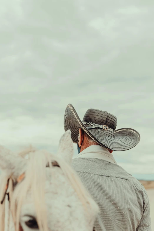 a man with a hat standing beside a white horse