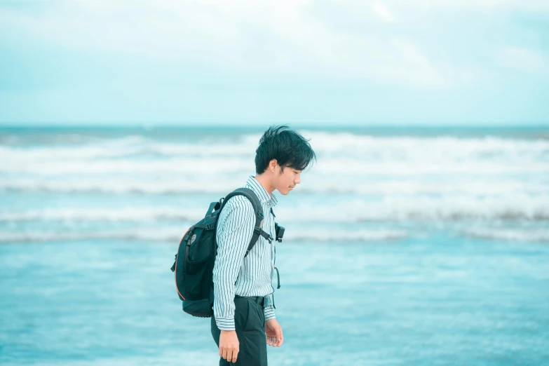 young man walking on beach by water's edge