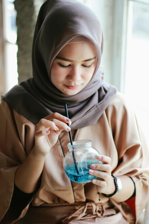 a young woman is holding a glass and smelling it