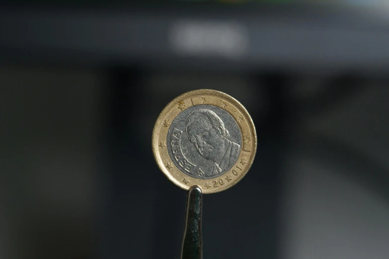 a coin on the end of a green stick