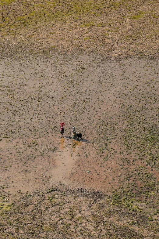 an aerial view of two people walking in the dirt