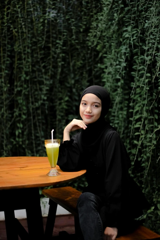 woman sitting with a drink in front of a table