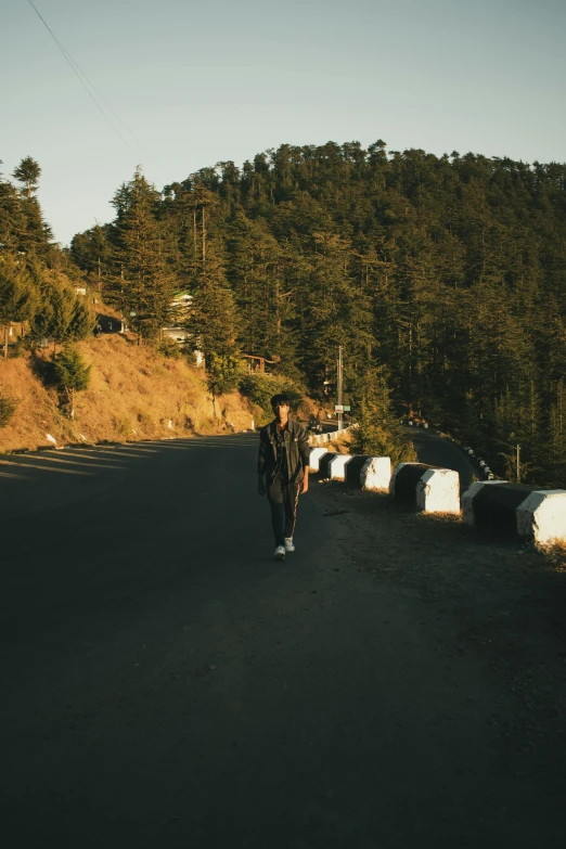 a person walking down a road in front of some round bales