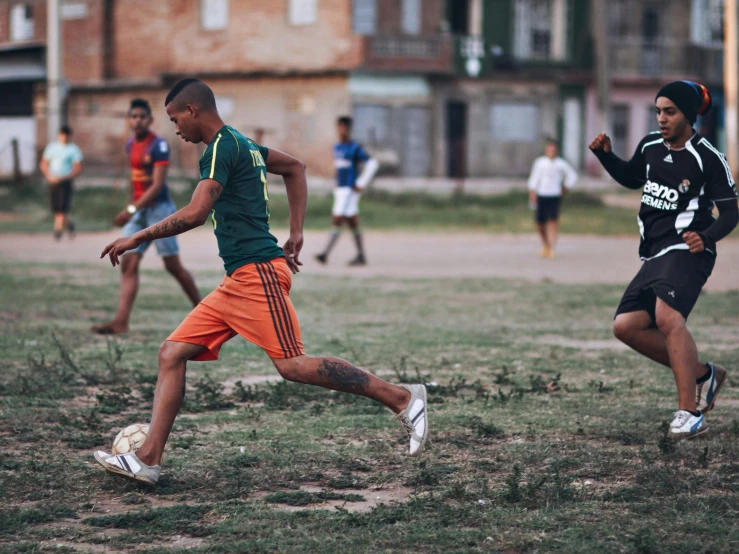 men running while a boy is attempting to kick the ball