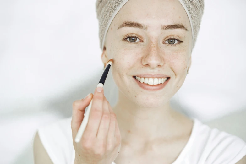 a woman smiling and holding a small pen in her hand