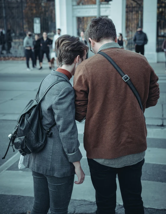 two people standing near each other on a sidewalk