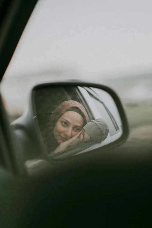 a woman taking a picture of herself in a rear view mirror
