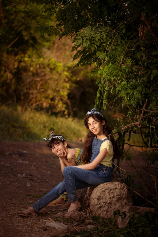 two children posing for the camera in front of some trees