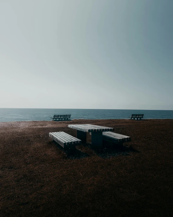 an empty beach with a few benches facing the water