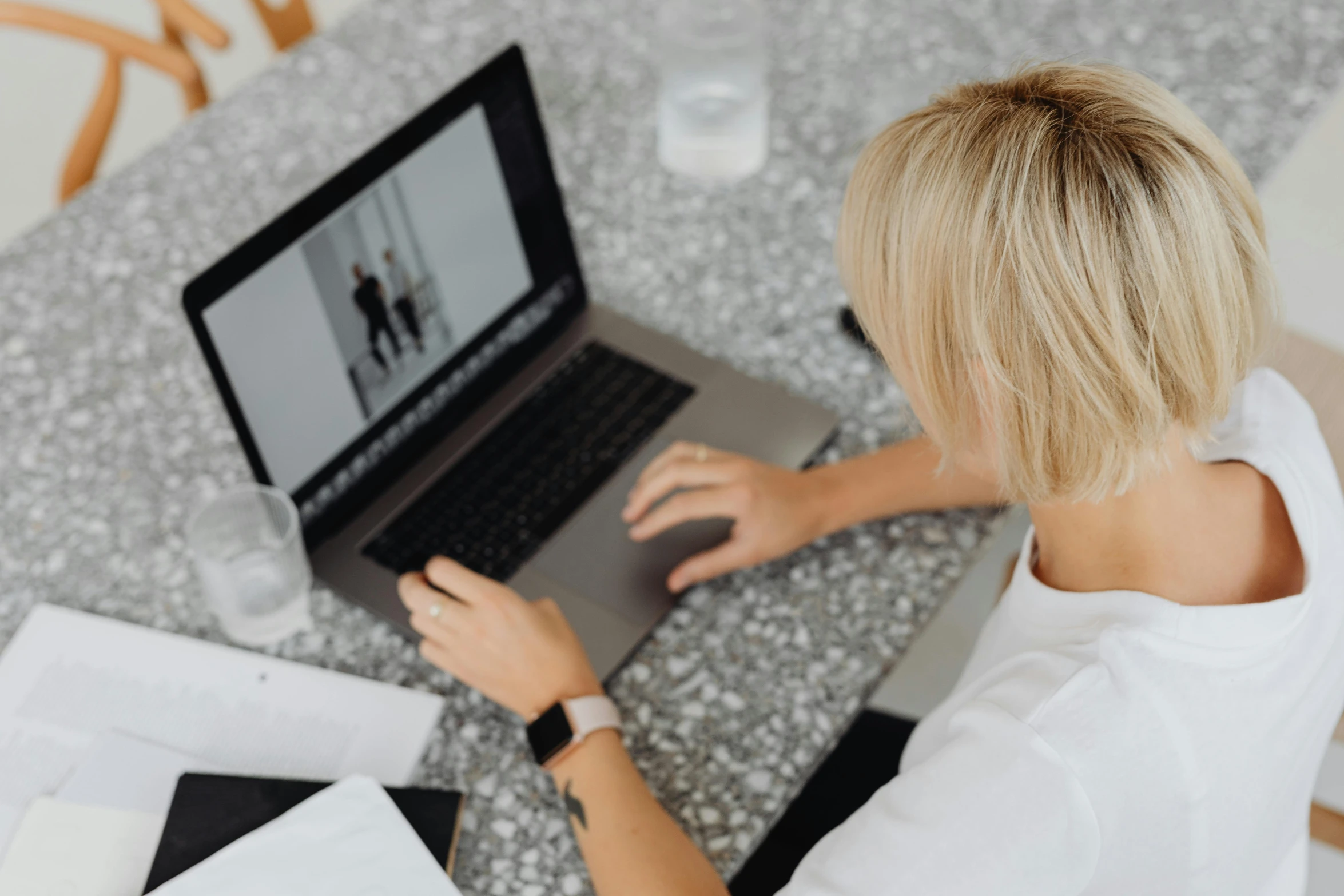 a woman is sitting at the table typing on her laptop