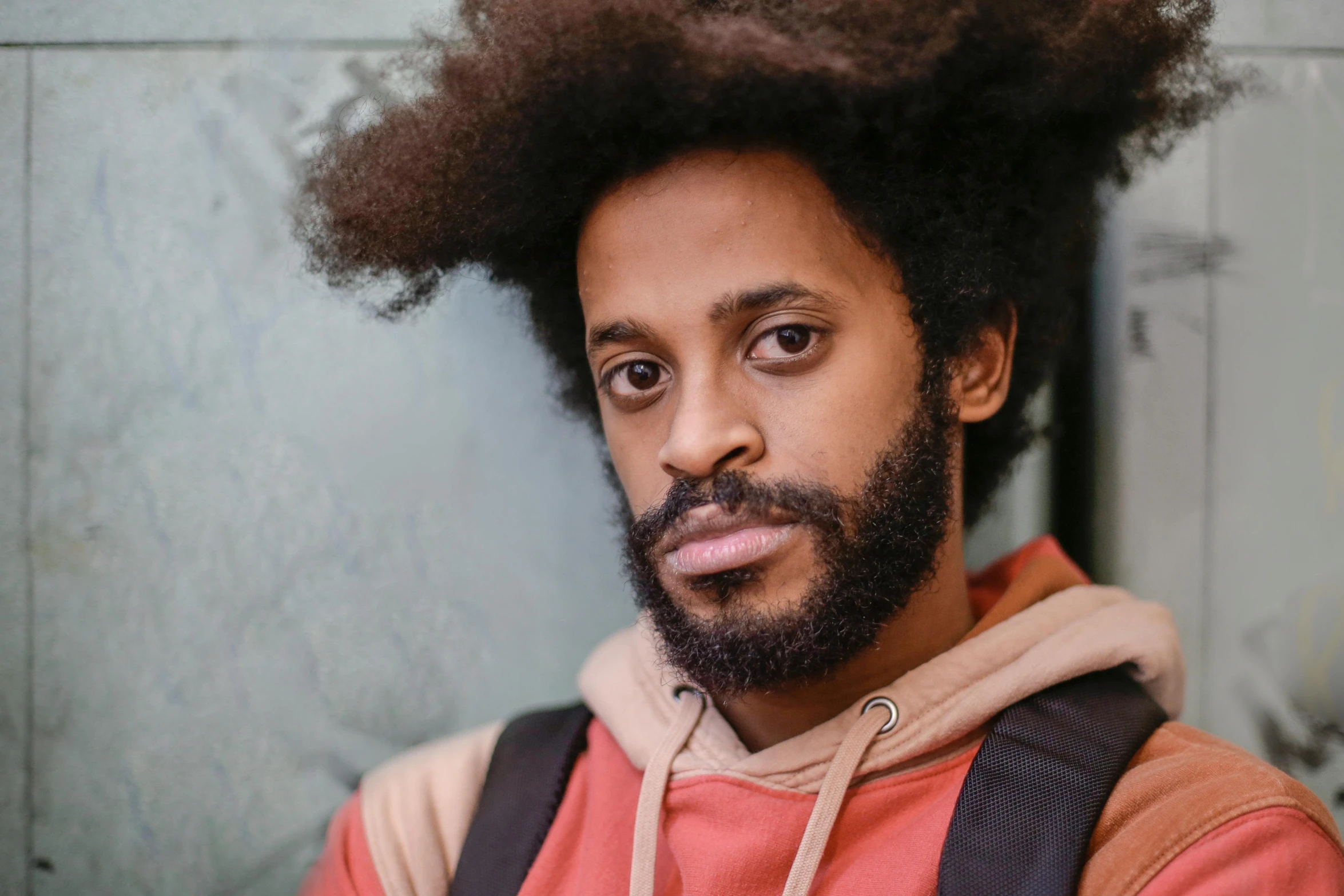 a man with large afro wearing an orange hoodie