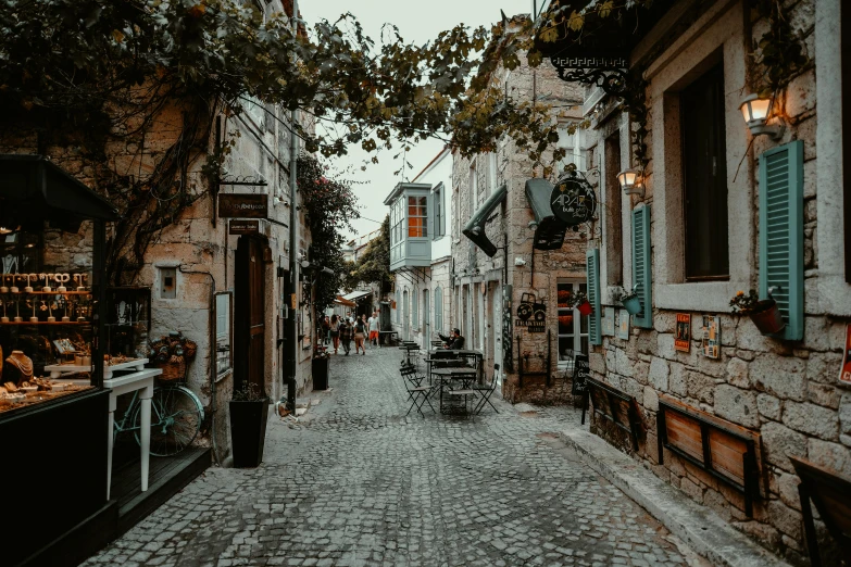 there is a cobble stone street with benches and tables lining both sides