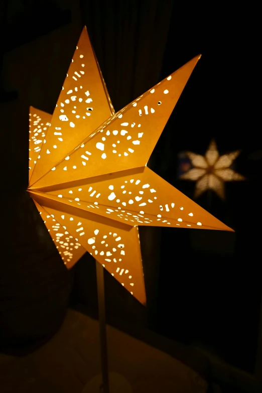 a lighted paper star on the floor next to a window