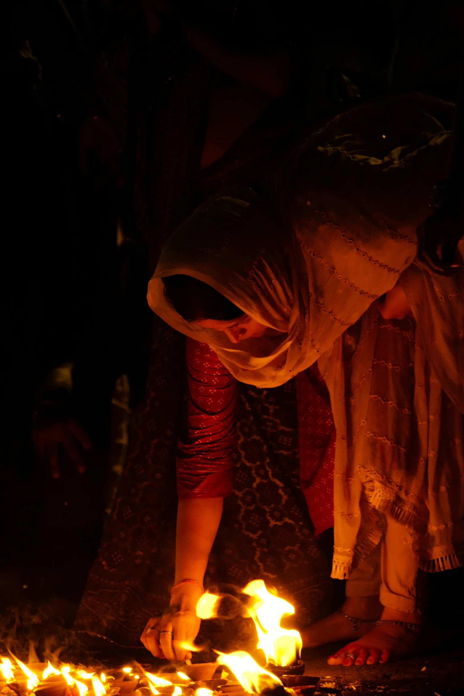 a group of people stand around burning wood