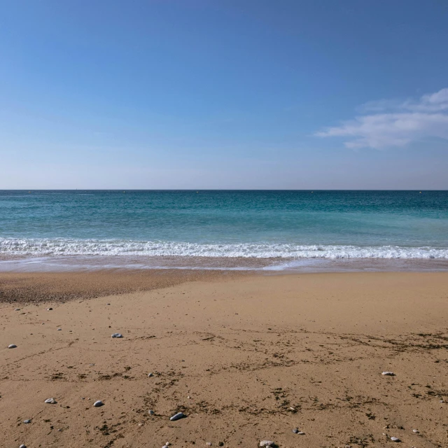 a surfboard on the beach next to a bright blue ocean