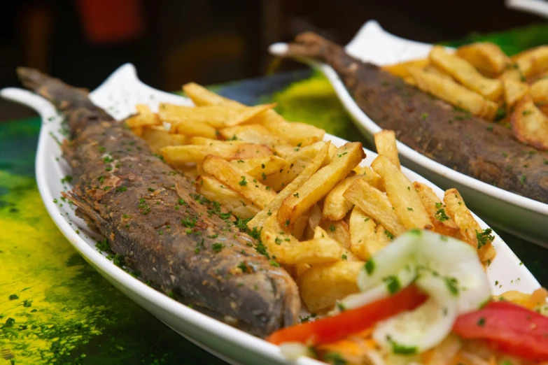 two plates filled with french fries and meat on a counter