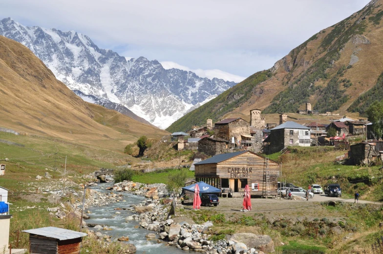 a stream running between the mountains with houses in it