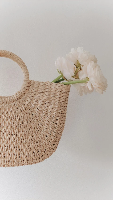 the flower is lying on top of a straw purse