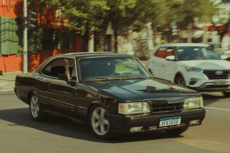 a black car driving down the street next to a white car