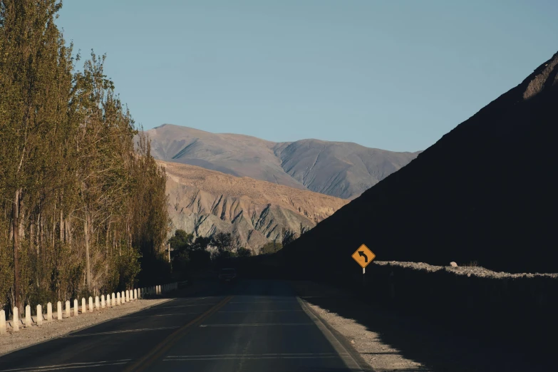 a sign sits on a road near a mountain range