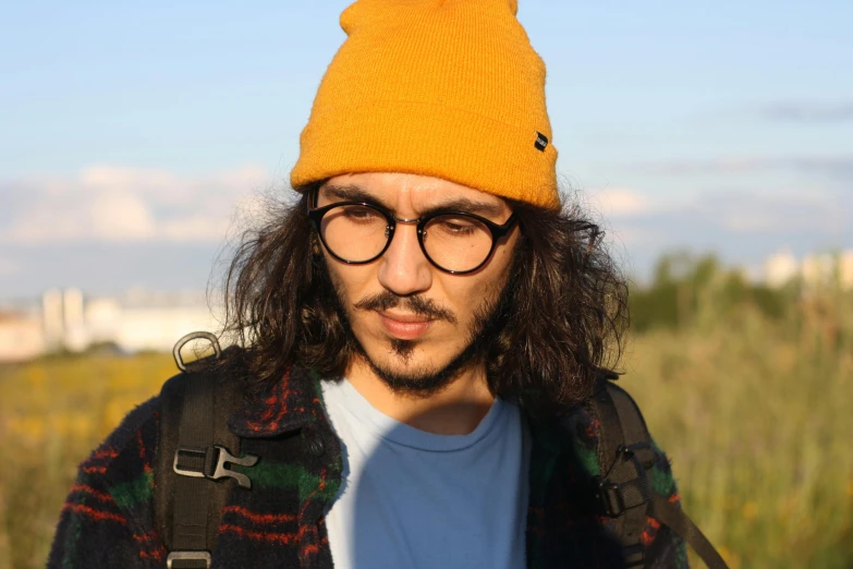a man with glasses and long hair wearing a hat