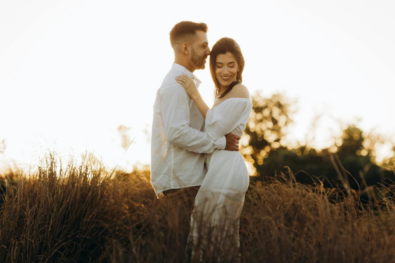 two people standing in tall grass holding each other