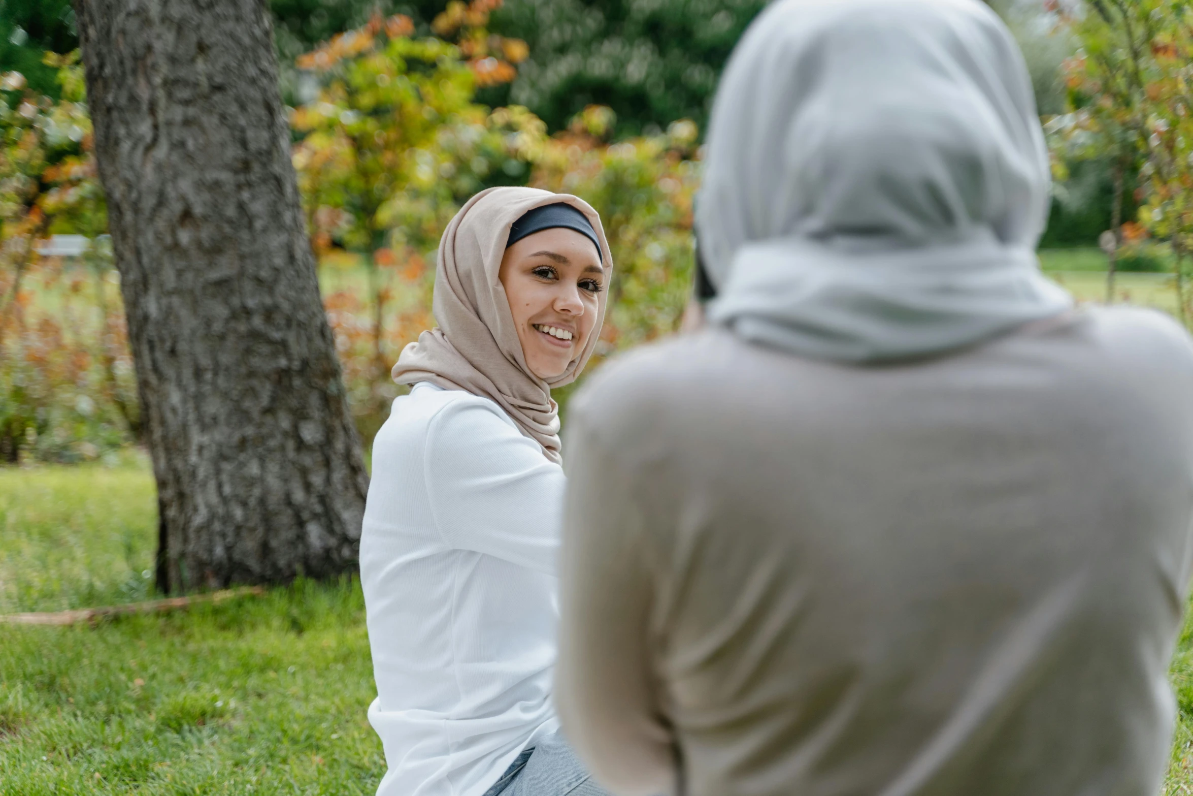 a woman in a headscarf smiles as she looks at another woman
