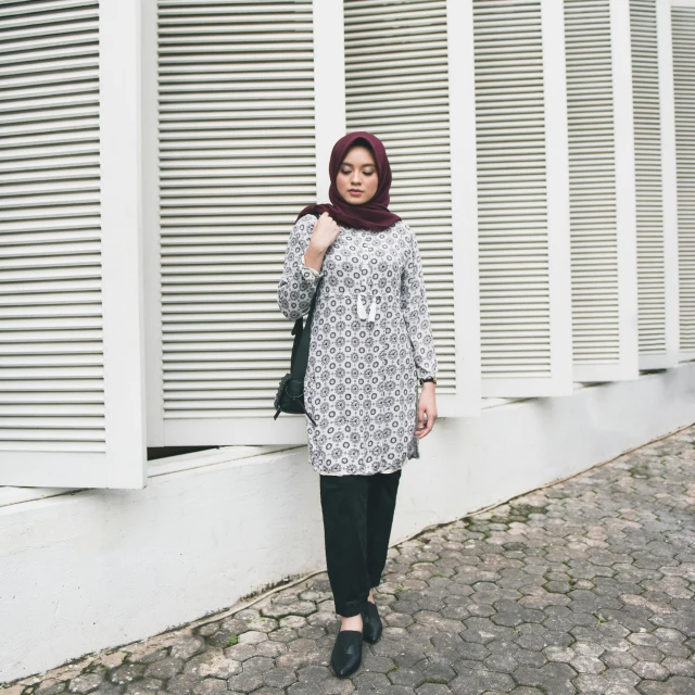 a woman standing against a white building