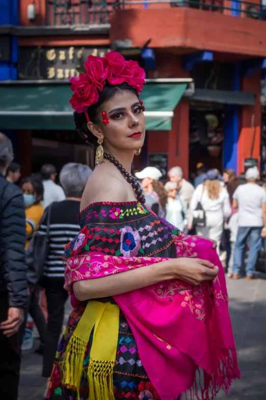 an woman in native costume stands on a city street