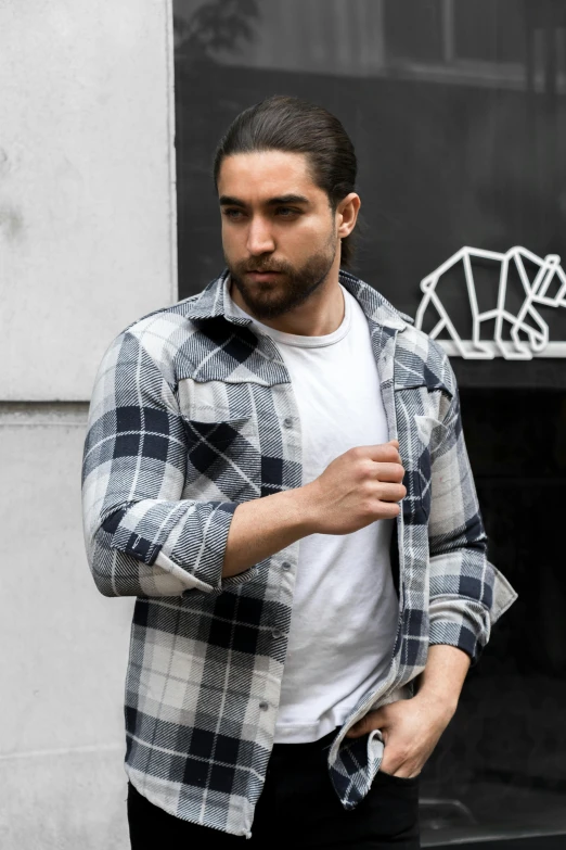 a young man is wearing a checked jacket while standing outside