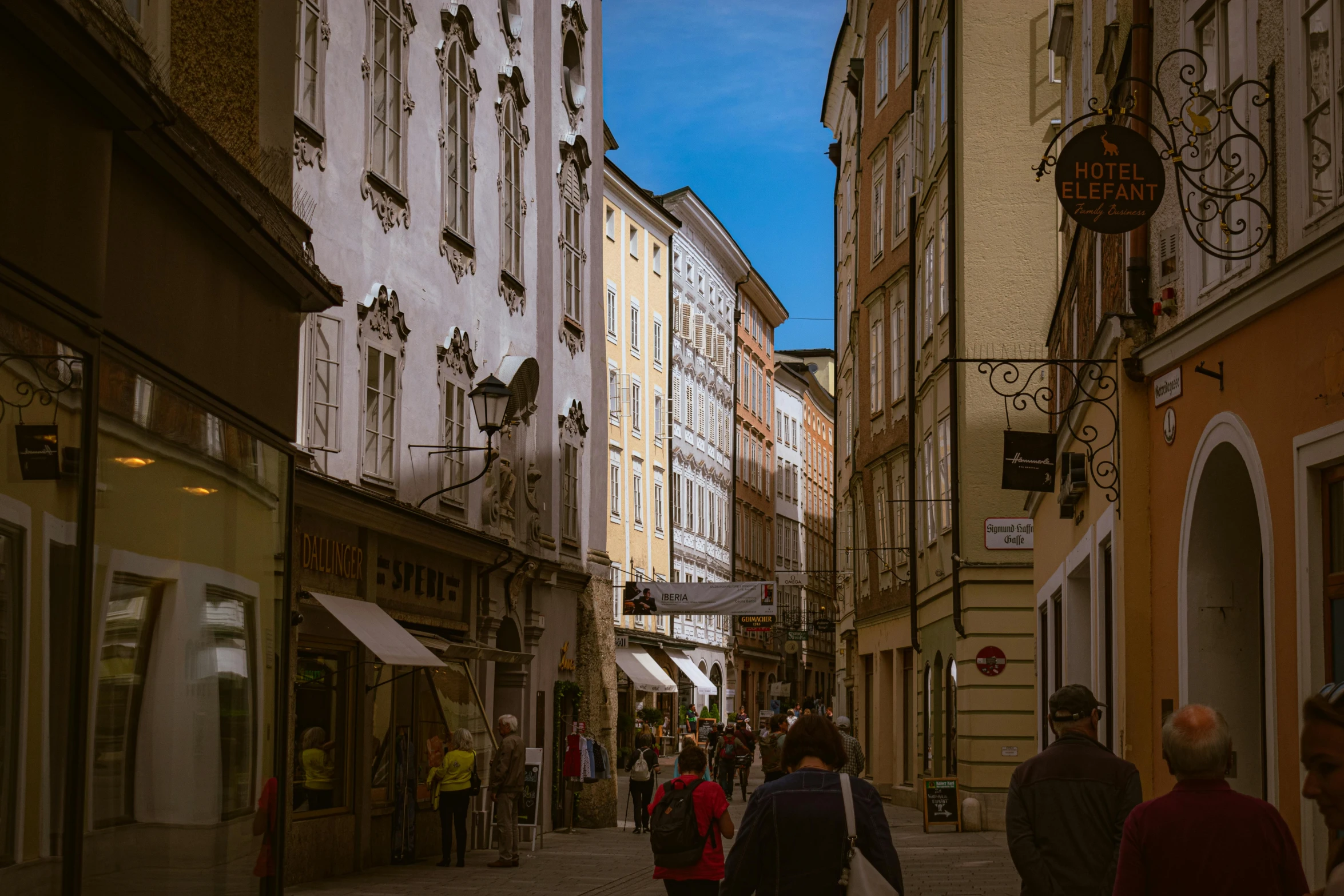 a group of people walking down a street next to tall buildings