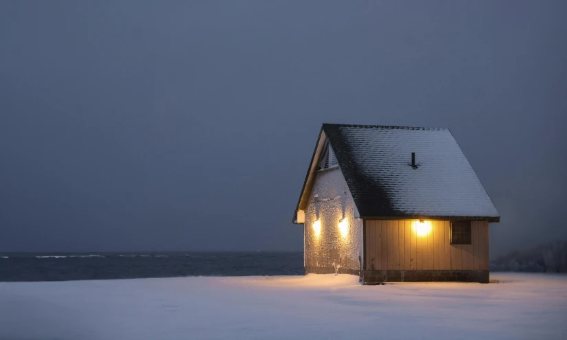 the light is on outside the cabin in the snow