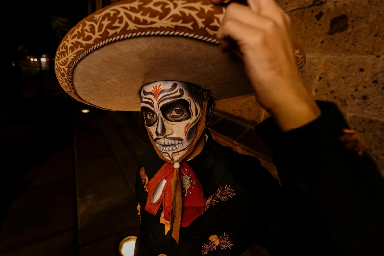 a man wearing a skull like face paint holding a hat