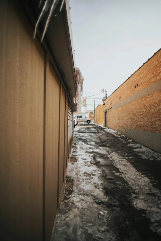 a long narrow alley with a parked vehicle in the background