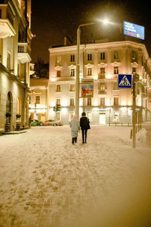 people walk in the snow down a city street