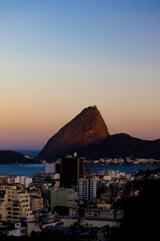 a large mountain rising above a city next to the ocean