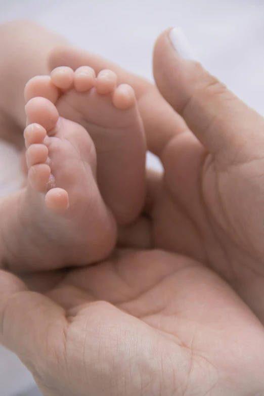 a person holding a baby's feet in their hands