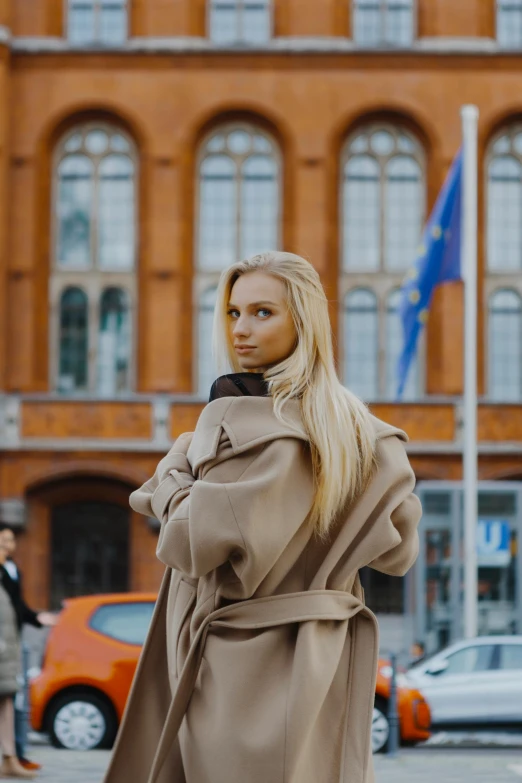 a woman is standing on the side of a street with her hands in her pockets