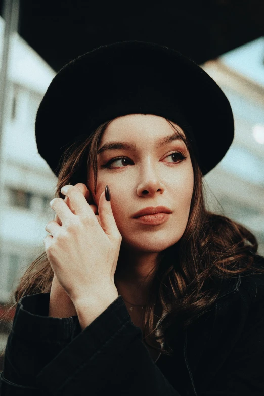 young woman with hat holding cell phone near face