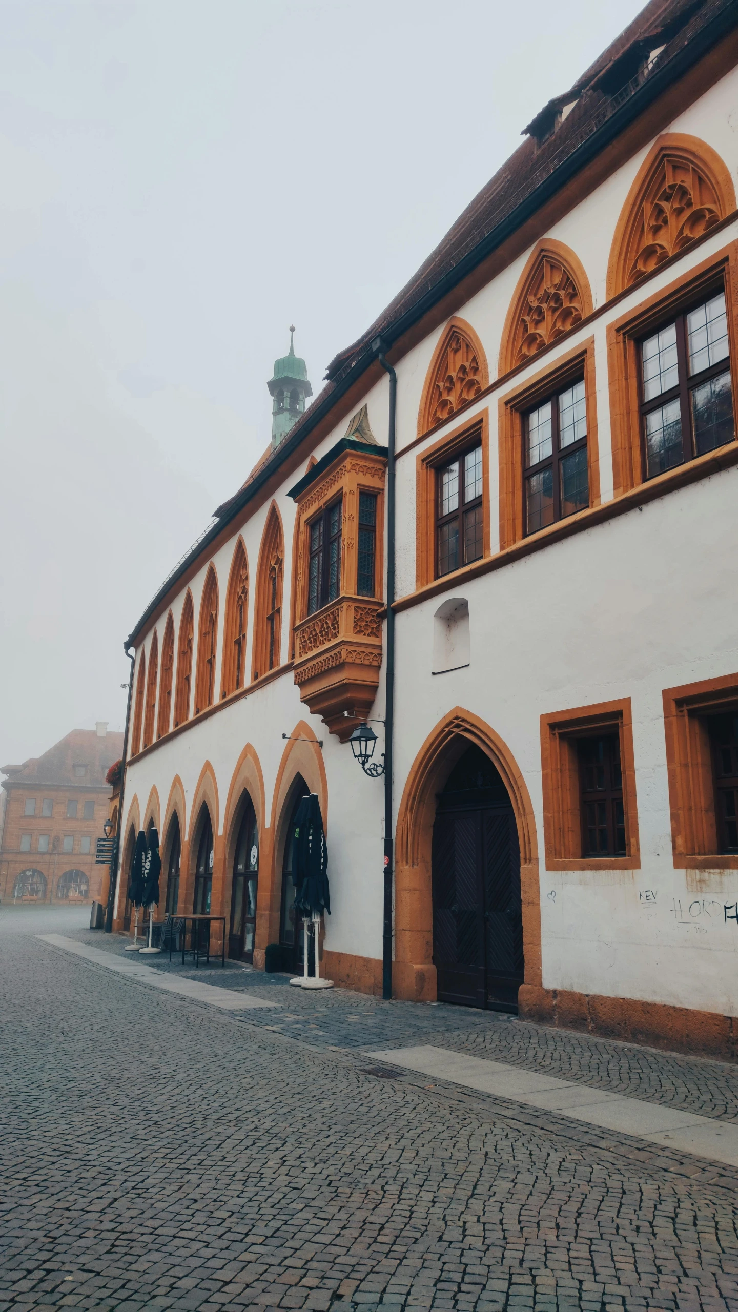 a cobblestone street leading to two buildings with arched wooden doors