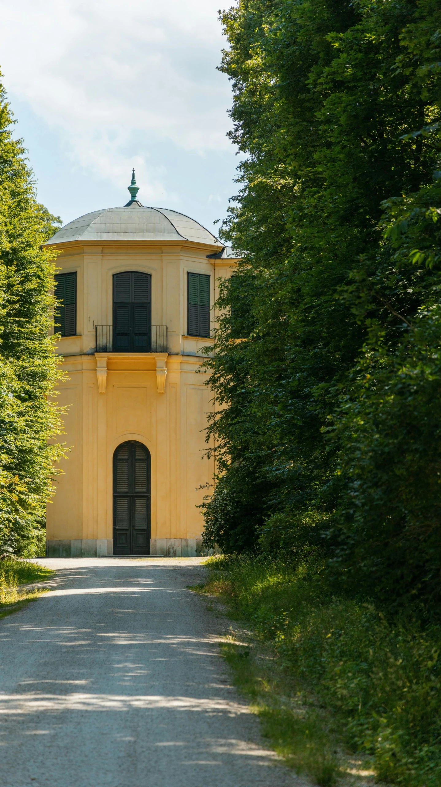 a long yellow house between two trees lined with greenery