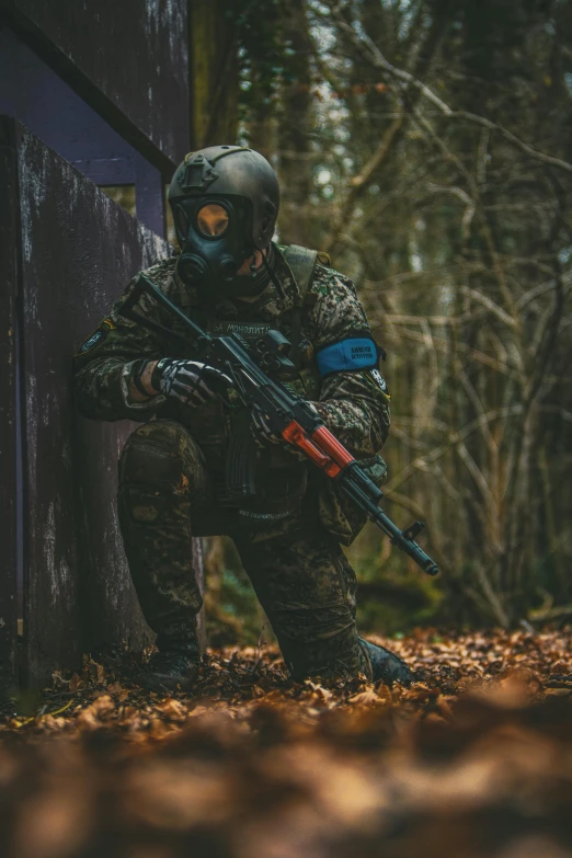 a man in camouflage is crouched by a building with guns