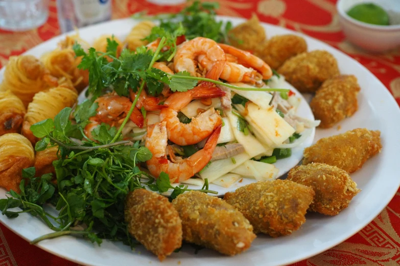 food that includes shrimp, potatoes and greens sits on a plate