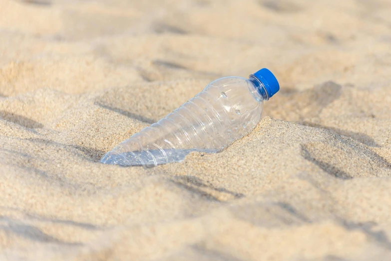 a plastic bottle lying in the sand at the beach