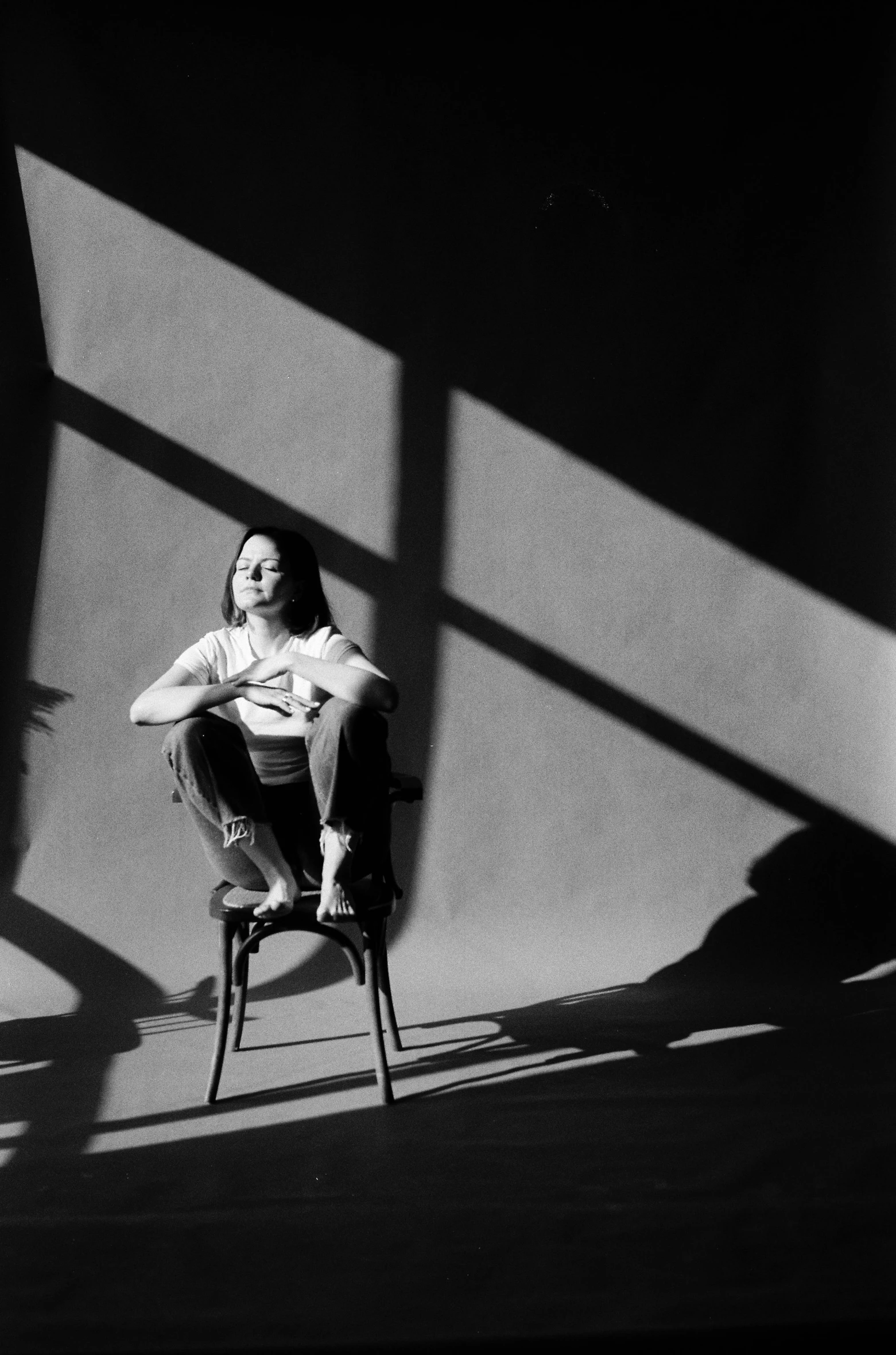 the woman is sitting on the chair in the shadow