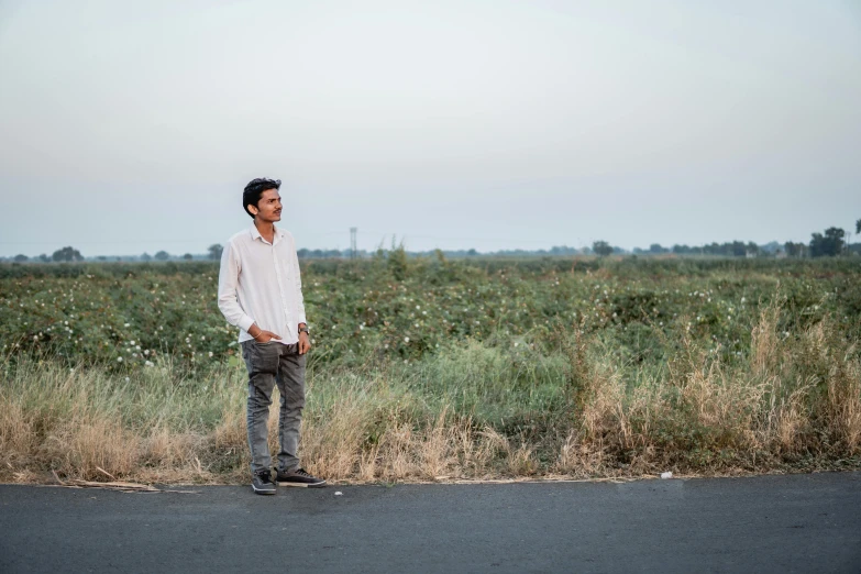 a man in a shirt standing on the side of a road