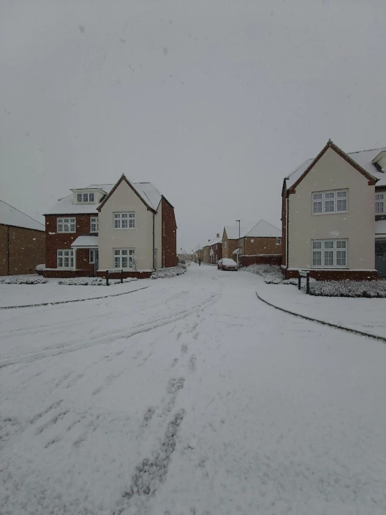 some houses and one car on a snowy street