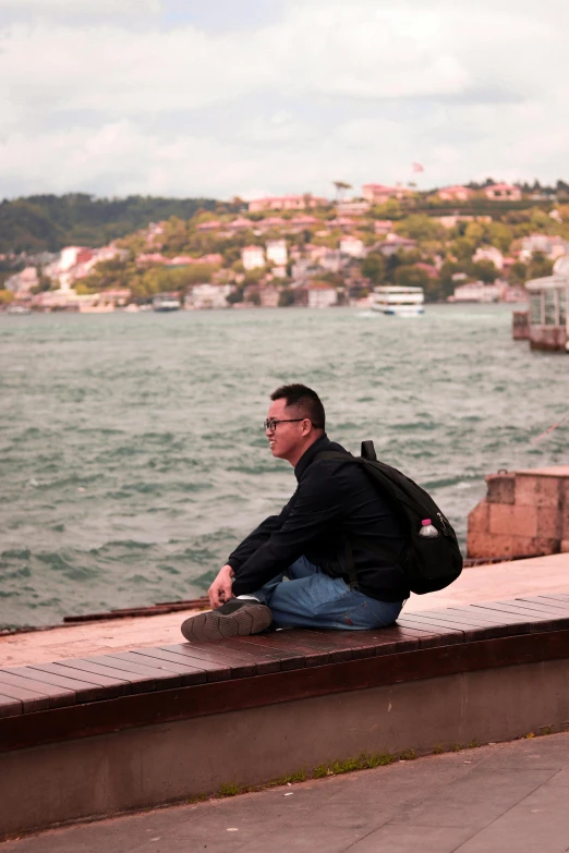 a man sitting on a ledge near the ocean
