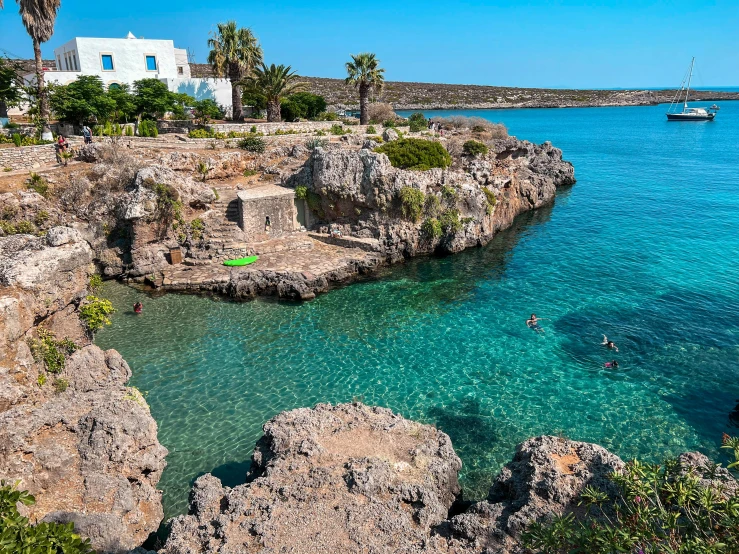 the small rocky coast is dotted with people swimming