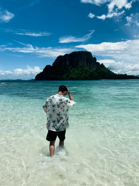 a man walking out of the water towards a mountain